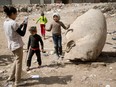 Children play around the head of a statue in a Cairo slum.The entire statue is about eight metres high.