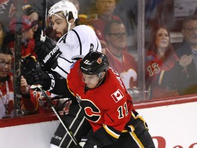 Los Angeles Kings' Drew Doughty, left, is checked into the boards by Calgary Flames' Mikael Backlund, during the first period in Calgary Wednesday.