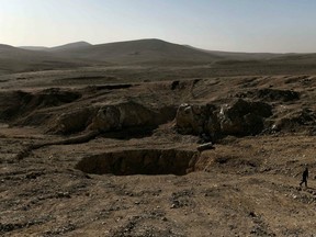 A member of the Hashed al-Shaabi paramilitaries, walks next to a sinkhole, known as the Khasfah, which has been used by ISIL as a mass grave, on February 26, 2017