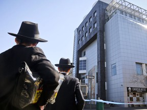 Two young men stop to view police activity outside the Jewish Children's Museum following a bomb threat, Thursday March 9, 2017 in Brooklyn