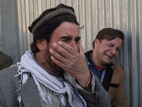Two Afghan men weep for their relatives in front of the main gate of a military hospital in Kabul on March 8, 2017, after a deadly attack claimed by the Islamic State group.