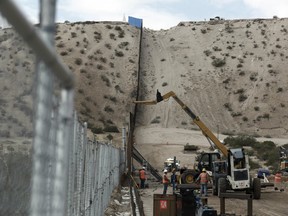 Workers continue work raising a taller fence in the Mexico-US border area separating the towns of Anapra, Mexico and Sunland Park, N.M.