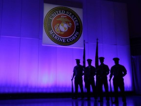 A U.S. Marine Corps Color Guard stands under a Marine Corps emblem in Jupiter, Fla. The Defense Department is investigating reports that some Marines shared naked photographs of female Marines, veterans and other women on a secret Facebook page.