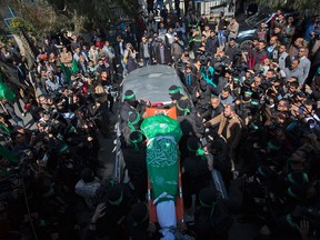 Masked gunmen carry the body of Hamas military commander Mazen Faqha during his funeral in Gaza City on March 25, 2017.