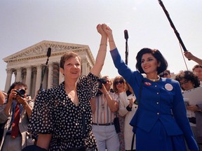 In this April 26, 1989 file photo, Norma McCorvey, Jane Roe in the 1973 court case, left, and her attorney Gloria Allred hold hands as they leave the Supreme Court building in Washington after sitting in while the court listened to arguments in a Missouri abortion case.