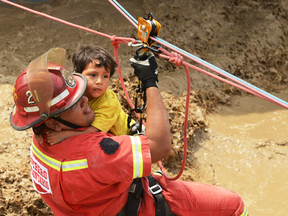 A rescue official helps a young boy across flood waters in Huachipa, Peru, on March 17, 2017.