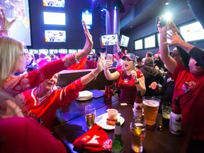 In this Feb. 21, 2014 file photo, Canadian hockey fans at a Toronto bar celebrate Canada's Olympic hockey semifinal win over the United States.