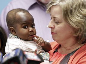 Foster mom Nancy Swabb holds Dominique, a 10-month-old baby born with two spines and an extra set of legs protruding from her neck during a news conference, Tuesday, March 21, 2017, at Advocate Children's Hospital in Park Ridge, Ill.