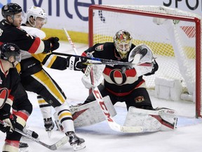 Ottawa Senators' goaltender Mike Condon knocks down a shot despite the presence of Oskar Sundquist of the Pittsburgh Penguins wreaking havoc in front during NHL action Thursday night in Ottawa. Condon was a standout with 34 saves as the Senators posted a 2-1 win in a shootout.