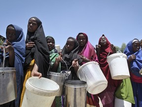 In this Saturday, Feb. 25, 2017 file photo, displaced Somali girls who fled the drought in southern Somalia stand in a queue to receive food handouts at a feeding center in a camp in Mogadishu, Somalia. Somalia's prime minister said Saturday, March 4, 2017 that 110 people have died from hunger in the past 48 hours in a single region as a severe drought threatens millions of people.