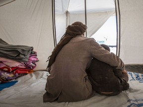 In this picture taken, Feb. 16, 2017, an Iraqi father, who fled violence in Mosul with his family, sits with his children in their tent in Al Hol Camp in Hasakah Governorate, Syria.