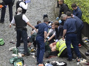 Conservative Member of Parliament Tobias Ellwood, centre, helps emergency services attend to an injured police officer outside the Houses of Parliament, London, Wednesday, March 22, 2017.