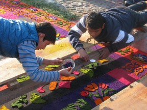 Men put the finishing touches on an elaborate sawdust pattern created on top of a cobblestone street in Antigua, Guatemala, in preparation for an Easter week procession.