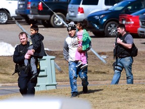 Police officers escort a family from the apartment complex to safety Wednesday, March 22, 2017, in Rothschild, Wis. The shootings happened at a bank, a law firm and an apartment complex, where officers, including a SWAT team, were in a standoff with the suspect late in the afternoon, Wausau police Capt. Todd Baeten said at a news conference.