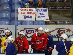 U.S. players practice in front of fans bearing signs before the start of the women's world hockey championships in Plymouth, Mich., on March 30.