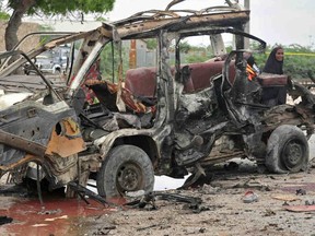 A woman walks at the scene of a suicide car attack near the Defense Ministry in Mogadishu