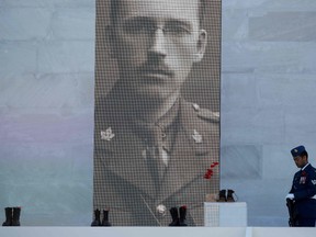 A soldier stands next to a sculpture of red poppies by artist Bernard Freseau and boots dropped off the Canadian National Vimy Memorial in Vimy, near Arras, northern France