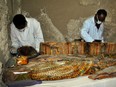 Members of the Egyptian archeological team work on a brightly coloured sarcophagus, April 18
