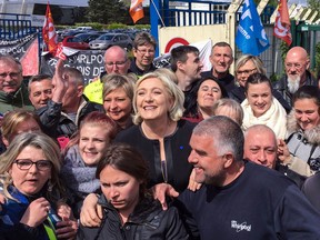 French presidential election candidate Marine Le Pen (C) smiles with people in front of the Whirlpool factory in Amiens, northern France, on April 26, 2017.