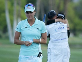 Lexi Thompson walks off the 18th green on April 2 while So Yeon Ryu celebrates with her caddie after the South Korean won a playoff over Thompson to earn victory at the ANA Inspiration.