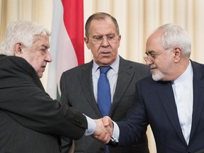 Russian Foreign Minister Sergey Lavrov, center, stands in the middle as Syrian Foreign Minister Walid Muallem, left, and Iranian Foreign Minister Mohammad Javad Zarif shake hands after a shared press conference following their talks focused on Syria in Moscow, Russia, Friday, April 14, 2017.