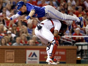 Toronto Blue Jays' Chris Coghlan leaps over Cardinals catcher Yadier Molina to score during the seventh inning of their game Tuesday night in St. Louis.