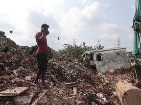 A Sri Lankan man speaks on his mobile phone at the site of buried houses in a collapse of a garbage dump in Meetotamulla, on the outskirts of Colombo, Sri Lanka, Saturday, April 15, 2017. A part of the garbage dump that had been used in recent years to dump the waste from capital Colombo collapsed destroying houses, according to local media reports.