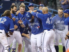 Kendrys Morales is mobbed at home plate by his Toronto Blue Jays teammates after hitting a game-winning solo home run in the bottom of the ninth inning at the Rogers Centre on April 15, 2017.