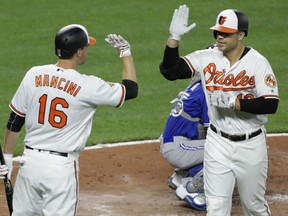 Chris Davis, right, high-fives Orioles teammate Trey Mancini after hitting a solo home run during the fourth inning against the Toronto Blue Jays in Baltimore on Wednesday night.