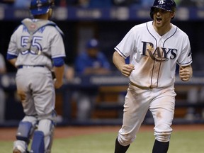 Toronto Blue Jays catcher Russell Martin heads to the dugout as Tampa Bay Rays' Brad Miller celebrates a game-winning walk that scored Mallex Smith during the 11th inning on Saturday, night in St. Petersburg, Fla.