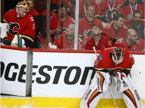 Flames goalie Brian Elliott (L) looks on from the bench as Chad Johnson concentrates durng a break in play during NHL playoff game 4 action between the Calgary Flames and Anaheim Ducks in Calgary, Alta on Wednesday April 19, 2017. Johnson replaced Elliott after one shot on net, which was a Ducks' goal.
