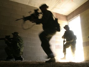 Members of the 3rd battalion of The Royal Canadian Regiment battle group storm a building during urban warfare exercises at CFB Petawawa on June 16, 2003 before deployment to Afghanistan.