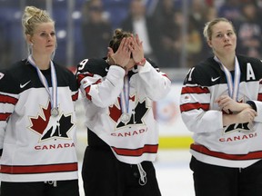 Canada's Bailey Bram, from left, Marie-Philip Poulin, and Haley Irwin stand dejectedly during the medal ceremony after the gold-medal game against the United States at the women's world hockey championship Friday night in Plymouth, Mich. The U.S. won 3-2 in overtime.