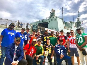 CFL players who are visiting Canadian military bases overseas to help boost morale pose with the Grey Cup by HMCS St. John's in a handout photo. A group of league players and personnel are visiting Canadian troops in Lviv, Ukraine and Marseilles, France.