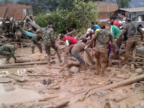 In this handout photo released by the Colombian National Army, soldiers and residents work together in rescue efforts in Mocoa, Colombia, Saturday, April 1, 2017, after an avalanche of water from an overflowing river swept through the city as people slept. The incident triggered by intense rains left at least 100 people dead in Mocoa, located near Colombia's border with Ecuador.