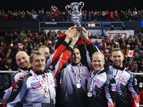 Team Canada, left to right, alternate Tom Sallows, coach Jules Owchar, lead Geoff Walker, second Brett Gallant, third Mark Nichols and skip Brad Gushue raise the trophy after defeating Sweden in the gold medal game at the Men's World Curling Championships in Edmonton, Sunday.