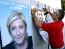 A supporter of French centrist presidential candidate Emmanuel Macron glues a campaign poster next to a poster of far-right candidate Marine le Pen, in Bayonne, southwestern France.