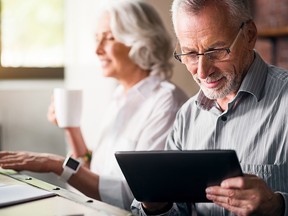 Daily life. Old grey man in glasses using laptop while woman drinking tea and smiling