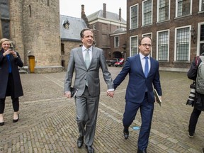 Dutch leader of the Democrats 66 (D66) party Alexander Pechtold, left, and party member Wouter Koolmee, right, arrive for a meeting with other Dutch political parties, at The Hague on April 1. They are holding hands to show solidarity for a gay couple that was attacked in the country.