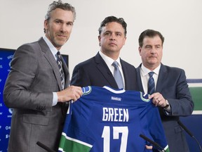 Vancouver Canucks president Trevor Linden, left, and general manager Jim Benning, right, introduce new head coach Travis Green on April 26.