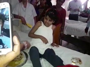 A young Indian girl  sits on a bed in a hospital in this image taken from video in Bahraich northern India Thursday April 6, 2017. Indian police are reviewing reports of missing children from recent years to try to identify the girl who was found in a forest with a group of monkeys.