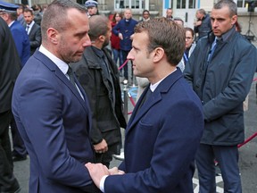 French presidential candidate Emmanuel Macron (R) shakes hands with Etienne Cardiles, the partner of the policeman killed by a jihadist in an attack on the Champs Elysees, on April 25, 2017, during a ceremony at the Paris prefecture building.