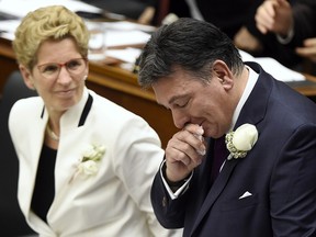 Ontario Finance Minister Charles Sousa, right, cries as he delivers the 2017 Ontario budget next to Premier Kathleen Wynne at Queen's Park in Toronto on Thursday, April 27, 2017.