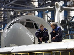 Workers sit on the wing of a Tupolev Tu-154M narrow-body aircraft