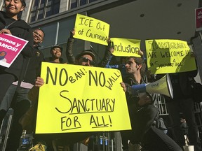 Protesters hold up signs outside a courthouse where a federal judge will hear arguments in the first lawsuit challenging President Donald Trump's executive order to withhold funding from communities that limit cooperation with immigration authorities Friday, April 14, 2017, in San Francisco.