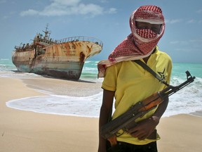 A masked Somali pirate stands in front of a Taiwanese fishing vessel in 2012.