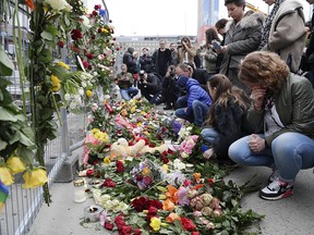 People lay down flowers at a fence near the department store Ahlens following a suspected terror attack in central Stockholm, Sweden, Saturday, April 8, 2017. Swedish prosecutor Hans Ihrman said a person has been formally identified as a suspect "of terrorist offences by murder" after a hijacked truck was driven into a crowd of pedestrians and crashed into a department store on Friday.