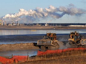 Workers use heavy machinery in the tailings pond at the Syncrude oil sands extraction facility near the town of Fort McMurray in Alberta Province, Canada on October 25, 2009.