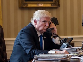 President Donald Trump speaks on the phone with Russian President Vladimir Putin in the Oval Office of the White House, January 28, 2017 in Washington, DC.