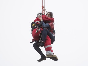 A rescuer saves a women stranded on the hook of a construction crane near Church Street and Wellesley Street in Toronto, Ontario, April 26, 2017